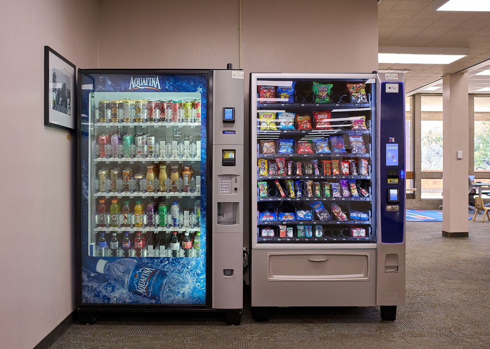 Snack and drink vending machines side by side in an office hallway